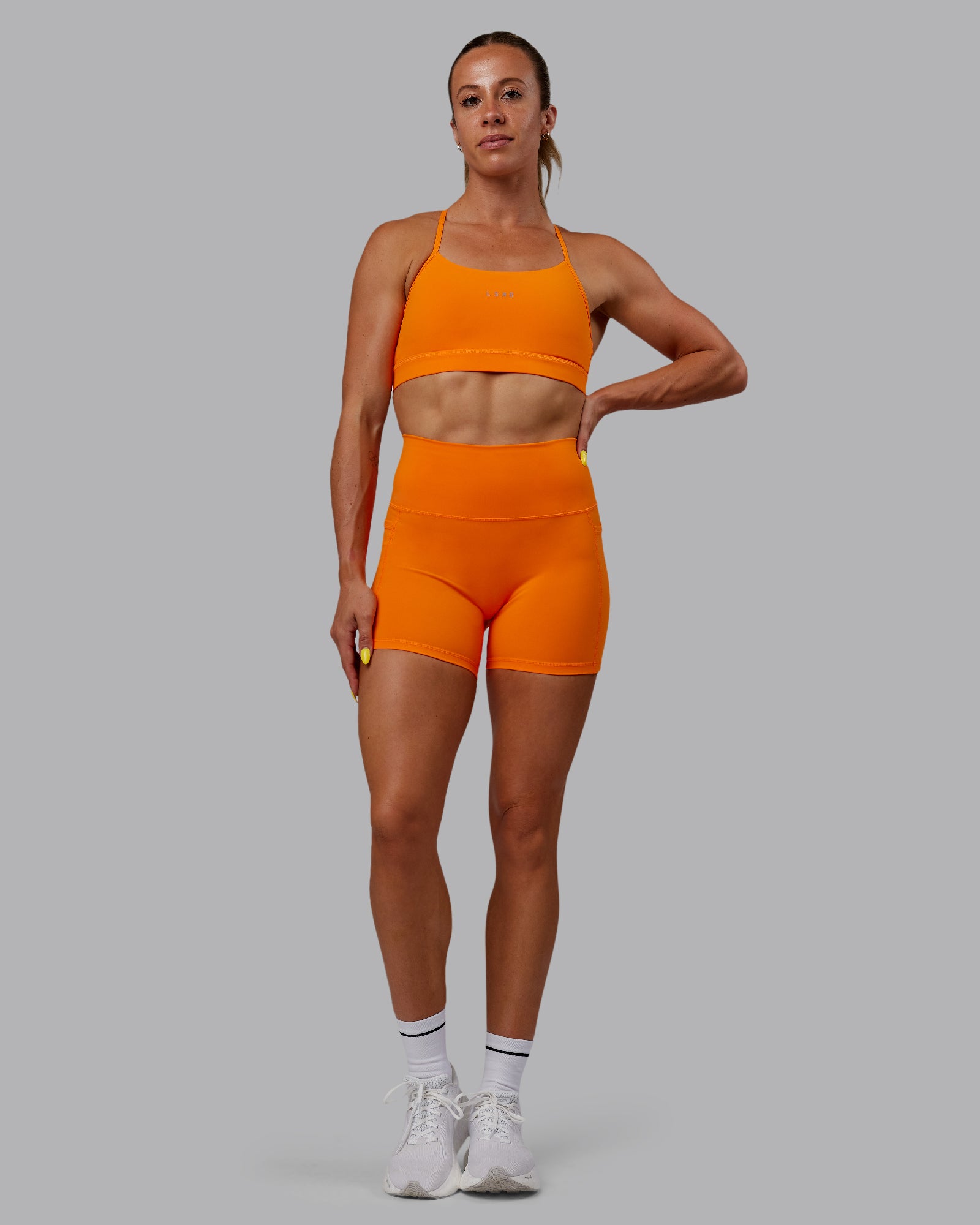 Woman wearing Fusion Ultra High-Rise 4" Short Pockets - Vibrant Orange | Model:Bree | Size:S