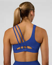 Woman wearing Galvanise Sports Bra 2.0 - Electric Indigo | Set:true | Angle:back | Model:Evie | Size:S