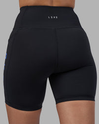 Woman wearing Rep Ultra High-Rise 6" Short Pockets - Black-Power Cobalt | Model:Rhiley | Size:S