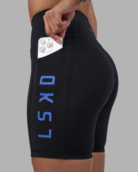 Woman wearing Rep Ultra High-Rise 6" Short Pockets - Black-Power Cobalt | Model:Rhiley | Size:S