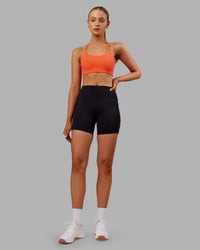 Woman wearing Rep Ultra High-Rise 4" Short Pockets - Black-Ultra Orange | Model:Ella | Size:S