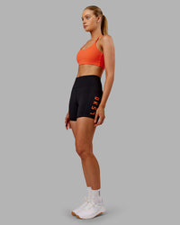 Woman wearing Rep Ultra High-Rise 4" Short Pockets - Black-Ultra Orange | Model:Ella | Size:S