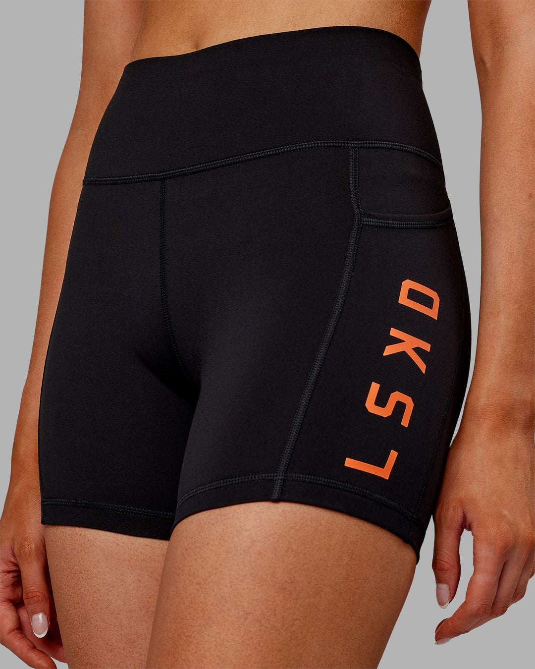 Woman wearing Rep Ultra High-Rise 4&quot; Short Pockets - Black-Ultra Orange | Model:Ella | Size:S