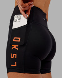 Woman wearing Rep Ultra High-Rise 4" Short Pockets - Black-Ultra Orange | Model:Ella | Size:S