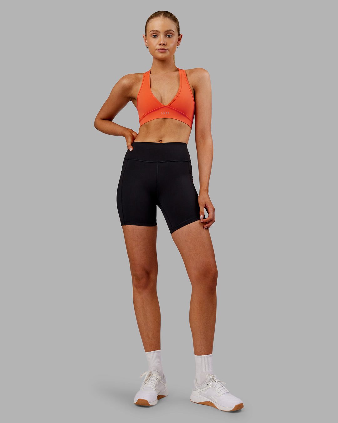 Woman wearing Rep Ultra High-Rise 6&quot; Short Pockets - Black-Ultra Orange | Model:Ella | Size:S