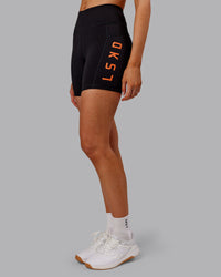 Woman wearing Rep Ultra High-Rise 6" Short Pockets - Black-Ultra Orange | Model:Ella | Size:S