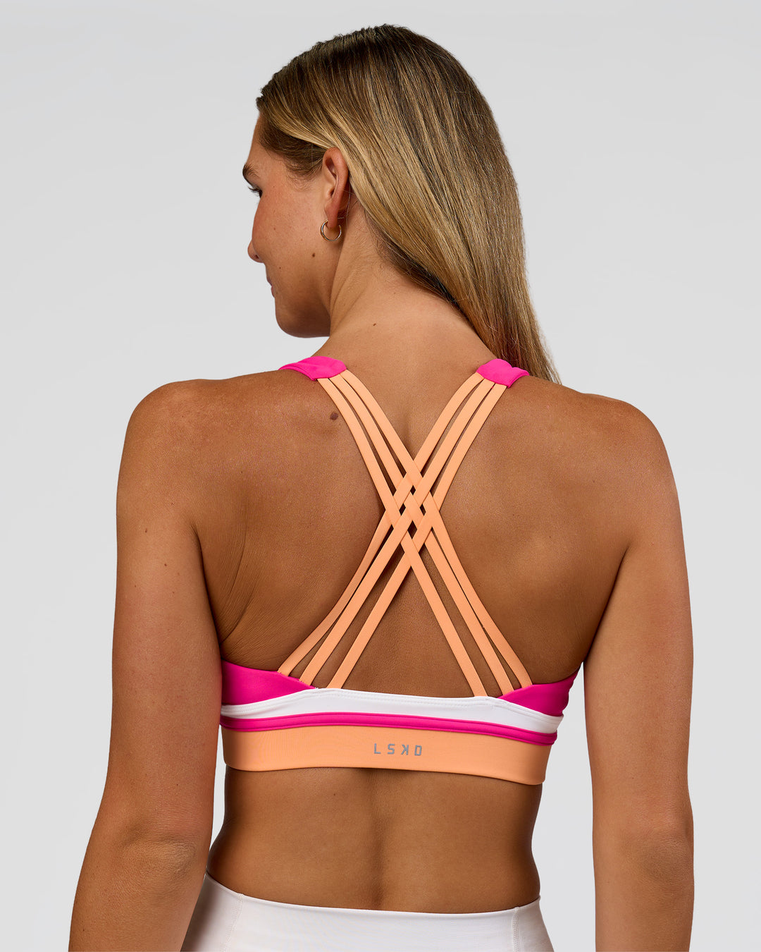 Woman wearing Revitalise Flash Sports Bra - Ultra Pink-Cantaloupe-White | Model:Amity | Size:S
