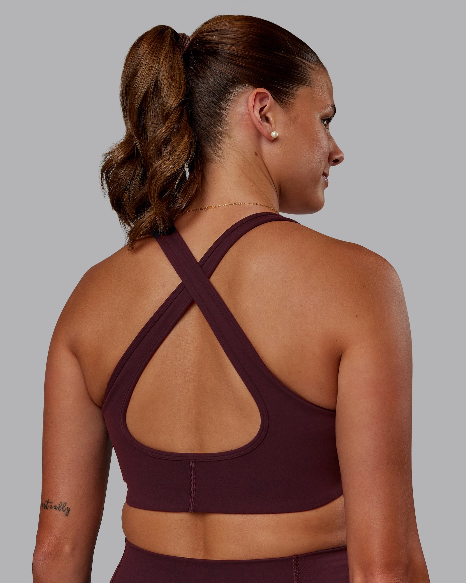 Woman wearing Stamina Sports Bra - Cherry Lacquer | Set:true | Angle:back | Model:Phoebe | Size:S
