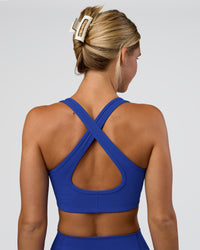 Woman wearing Stamina Sports Bra - Electric Indigo | Set:true | Angle:back | Model:Amity | Size:S