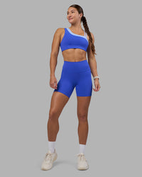 Woman wearing Thrive Asymmetric Sports Bra - Power Cobalt-Open Air | Model:Hannah | Size:S