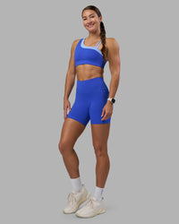 Woman wearing Thrive Asymmetric Sports Bra - Power Cobalt-Open Air | Model:Hannah | Size:S