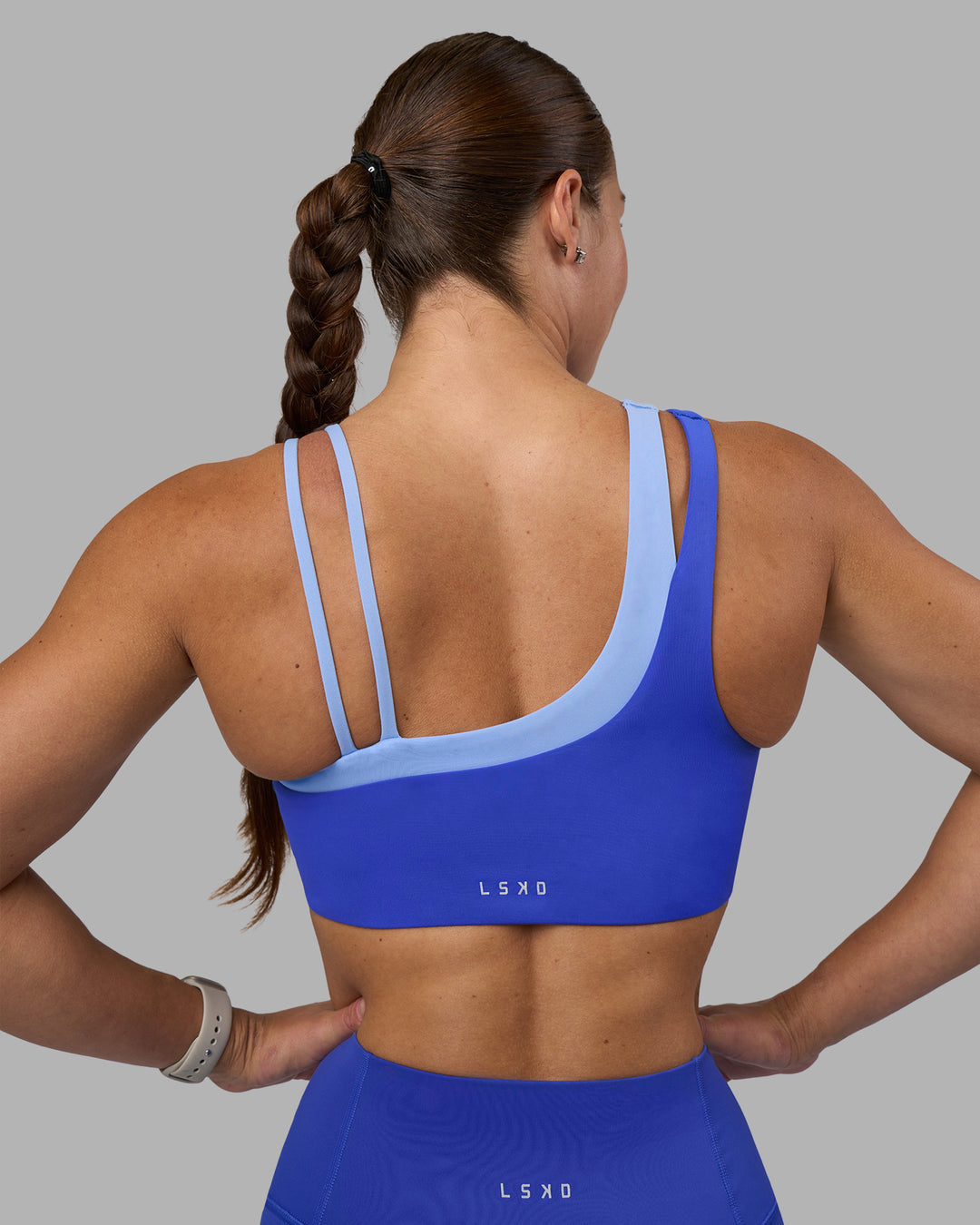 Woman wearing Thrive Asymmetric Sports Bra - Power Cobalt-Open Air | Model:Hannah | Size:S