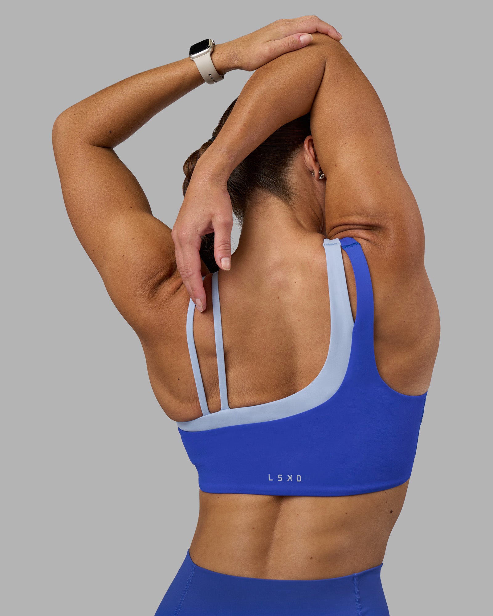 Woman wearing Thrive Asymmetric Sports Bra - Power Cobalt-Open Air | Model:Hannah | Size:S