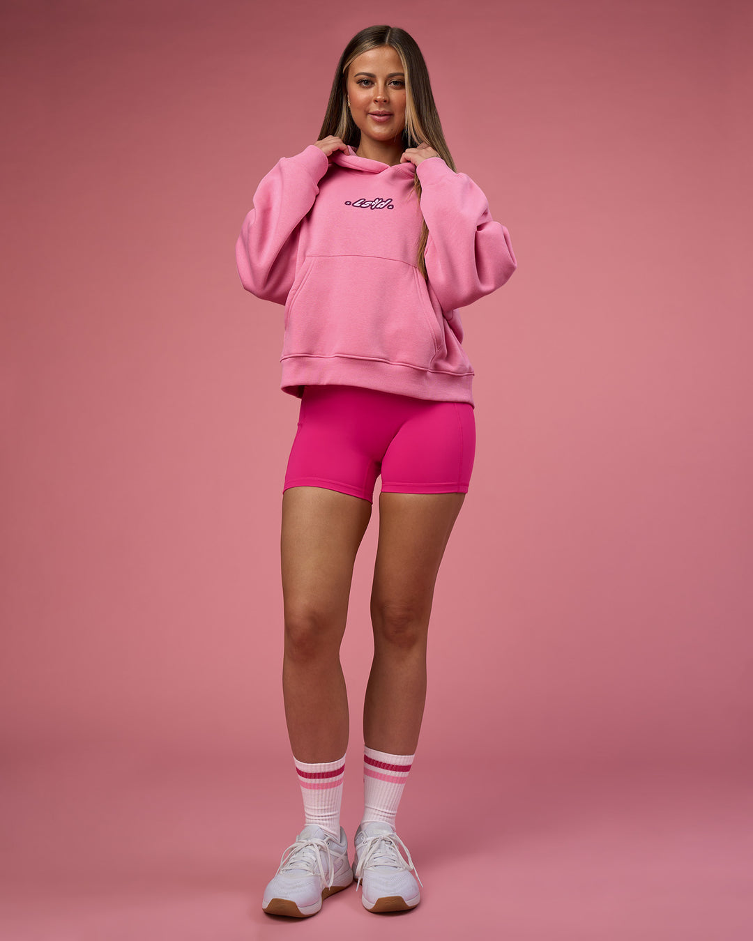 Woman wearing We Rise Post Train Cropped Hoodie - Candy Pink-Plum Caspia | Model:Tianah | Size:S