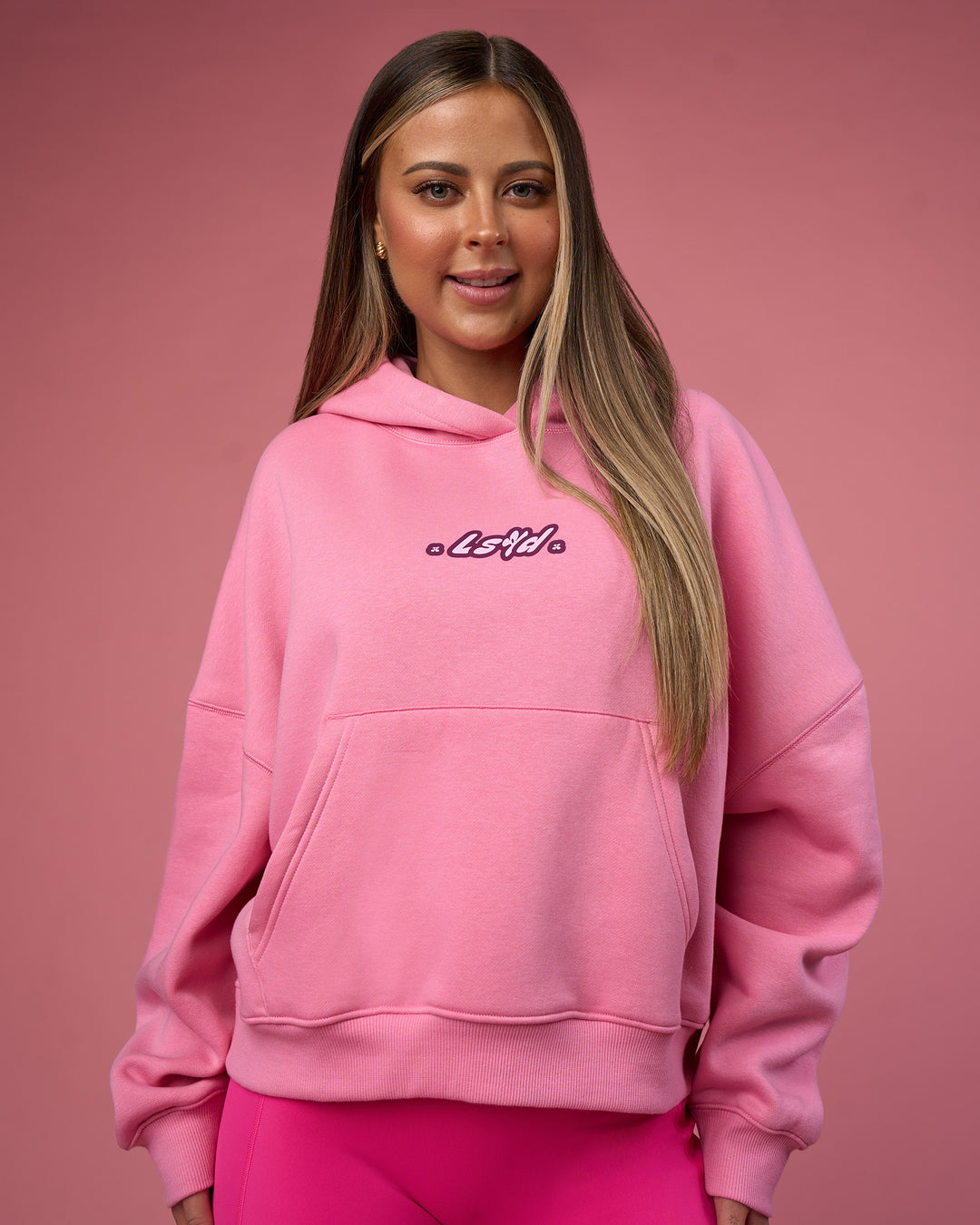 Woman wearing We Rise Post Train Cropped Hoodie - Candy Pink-Plum Caspia | Model:Tianah | Size:S