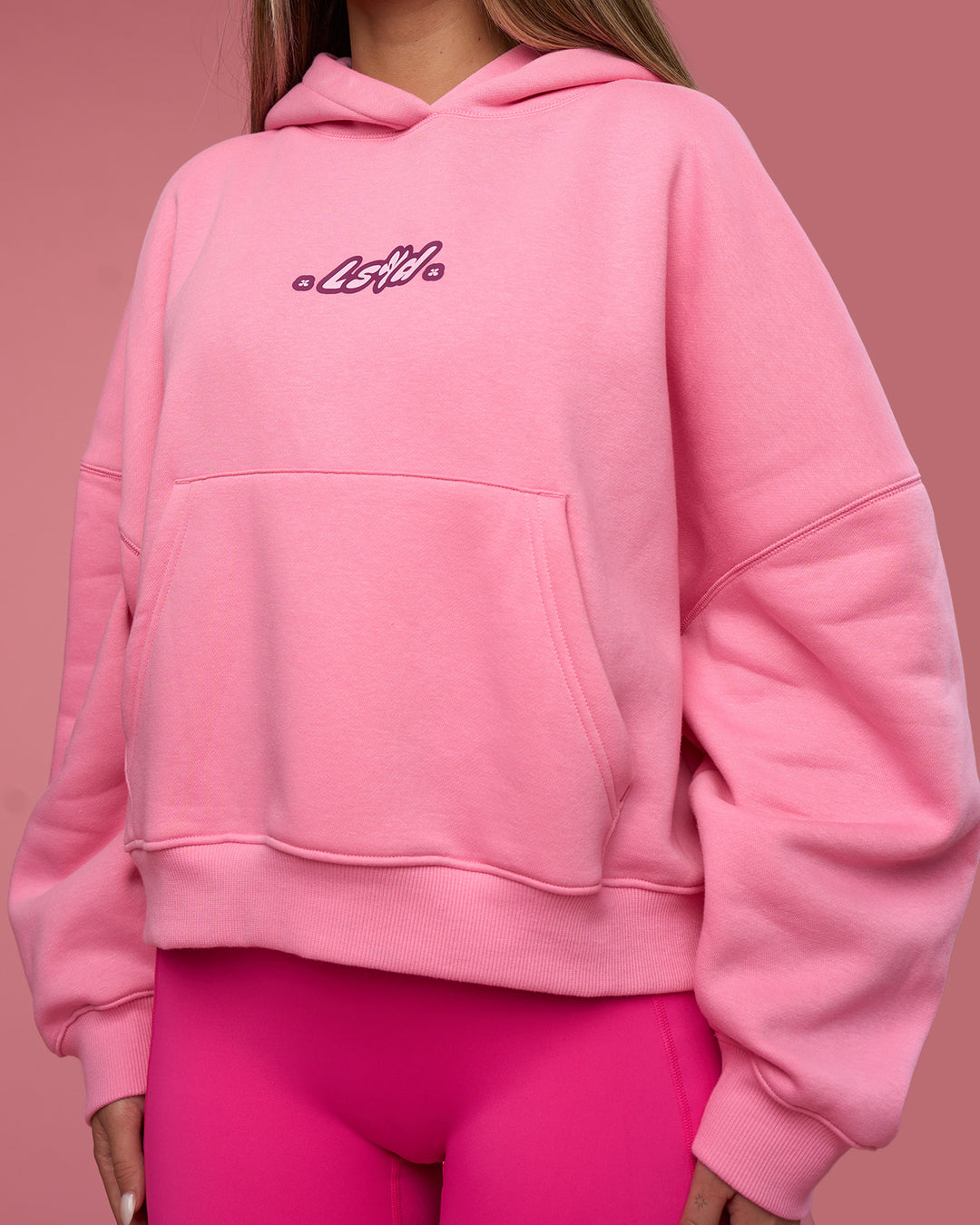 Woman wearing We Rise Post Train Cropped Hoodie - Candy Pink-Plum Caspia | Model:Tianah | Size:S