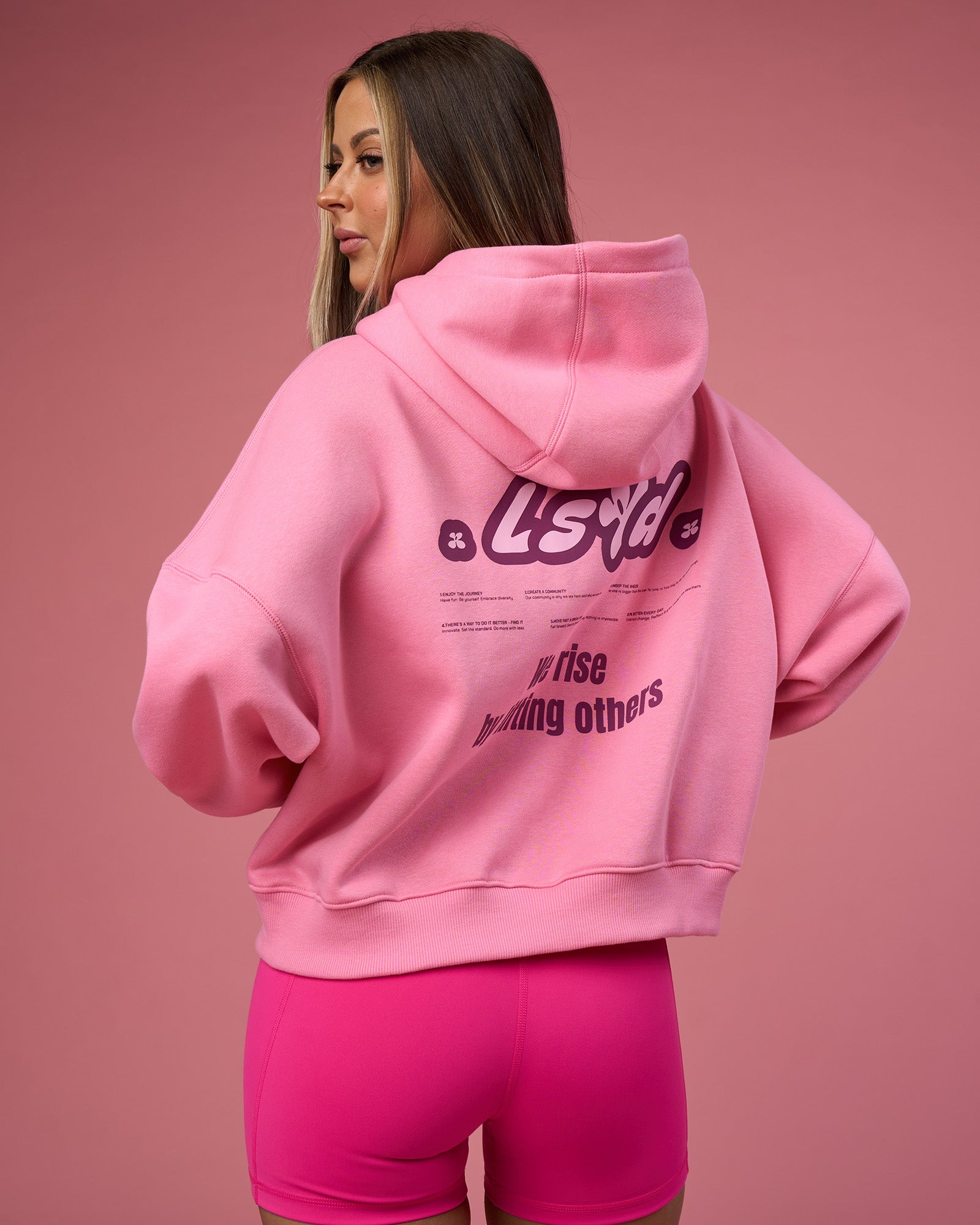 Woman wearing We Rise Post Train Cropped Hoodie - Candy Pink-Plum Caspia | Model:Tianah | Size:S