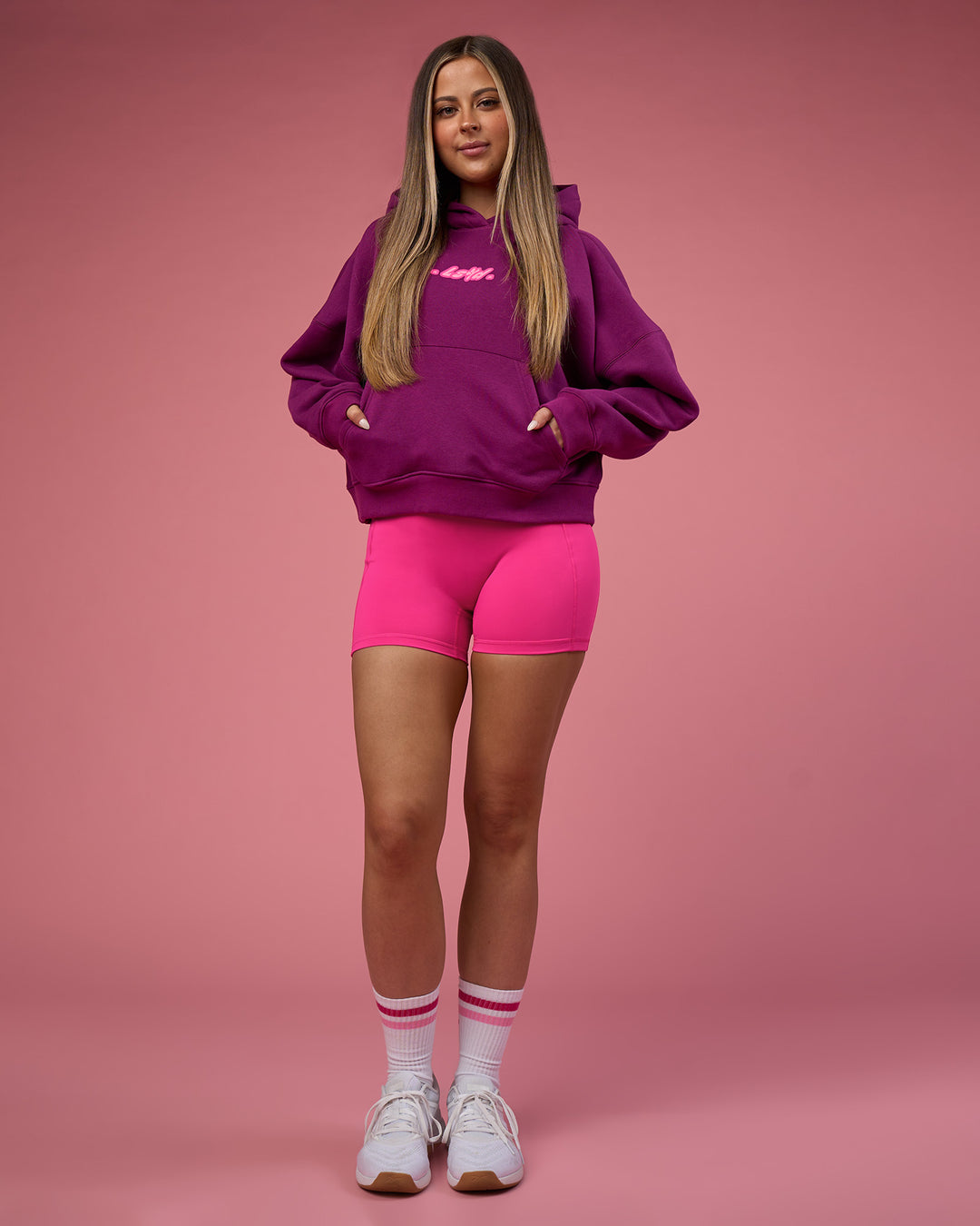 Woman wearing We Rise Post Train Cropped Hoodie - Plum Caspia-Ultra Pink | Model:Tianah | Size:S