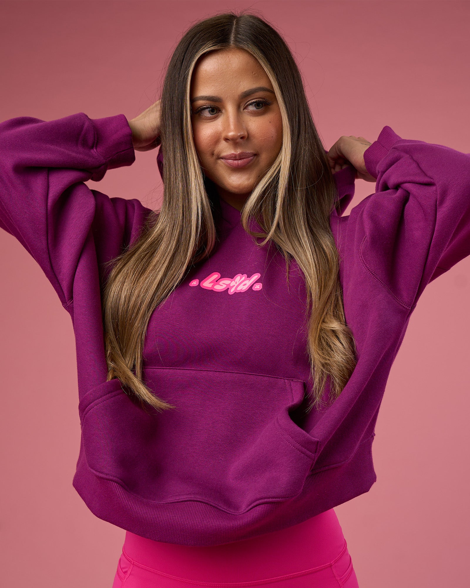Woman wearing We Rise Post Train Cropped Hoodie - Plum Caspia-Ultra Pink | Model:Tianah | Size:S
