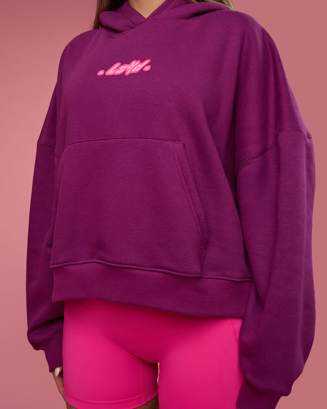 Woman wearing We Rise Post Train Cropped Hoodie - Plum Caspia-Ultra Pink | Model:Tianah | Size:S