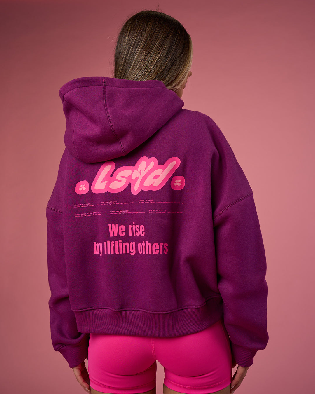 Woman wearing We Rise Post Train Cropped Hoodie - Plum Caspia-Ultra Pink | Model:Tianah | Size:S