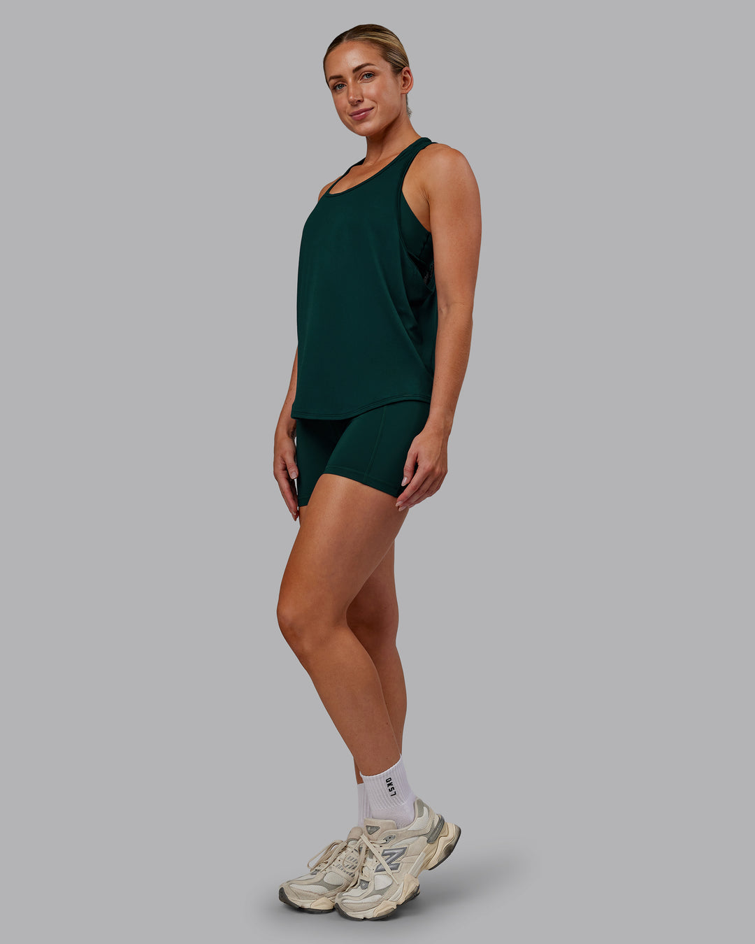 Woman wearing AeroFLX+ Drop Armhole Seamless Tank - Dark Moss | Model:Paris | Size:S