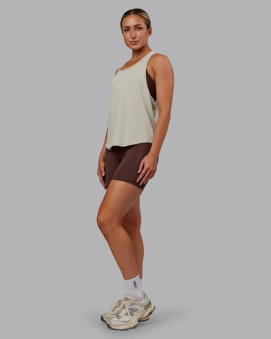 Woman wearing AeroFLX+ Drop Armhole Seamless Tank - Shale Beige | Model:Paris | Size:S