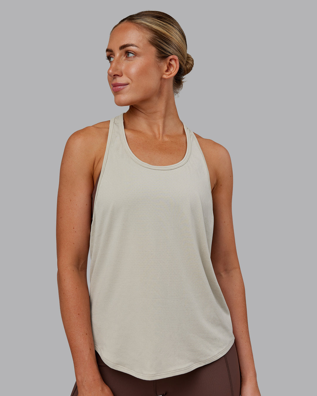Woman wearing AeroFLX+ Drop Armhole Seamless Tank - Shale Beige | Model:Paris | Size:S