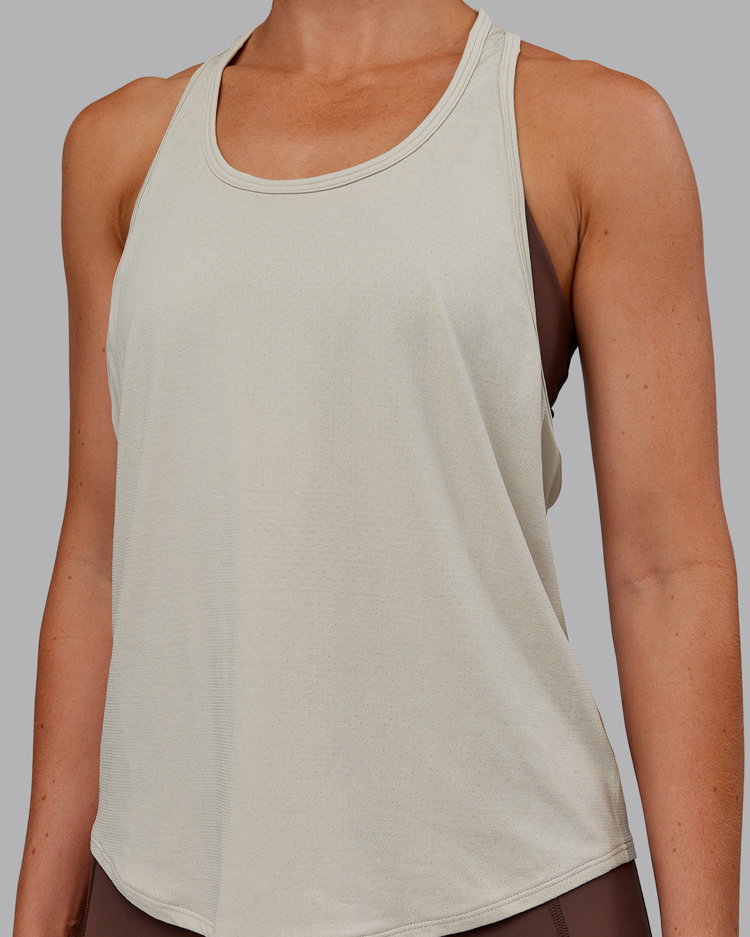 Woman wearing AeroFLX+ Drop Armhole Seamless Tank - Shale Beige | Model:Paris | Size:S