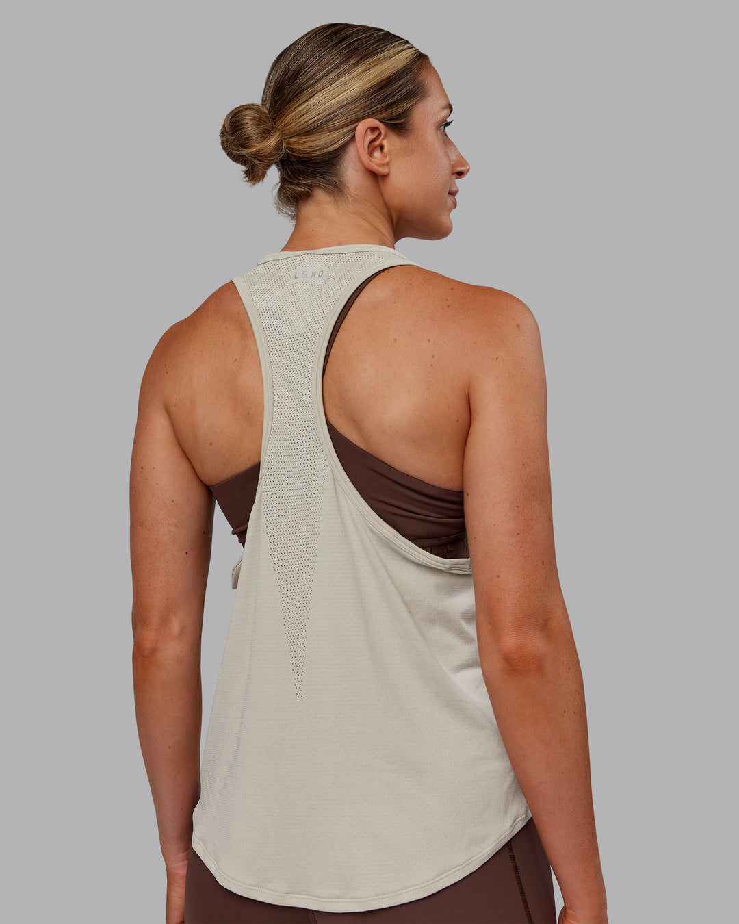 Woman wearing AeroFLX+ Drop Armhole Seamless Tank - Shale Beige | Model:Paris | Size:S