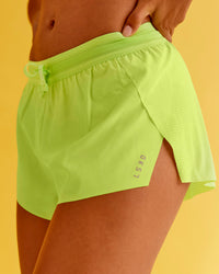 Woman wearing Accelerate 3" Mid-Rise Running Short - Hyper Green | Model:Txai | Size:XS