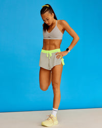 Woman wearing Accelerate 3" Running Short - Lime Glo-Shale Beige | Model:Steph | Size:XS