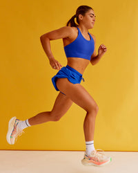 Woman wearing Accelerate Split Strap Sports Bra - Electric Indigo | Model:Bella | Size:XS