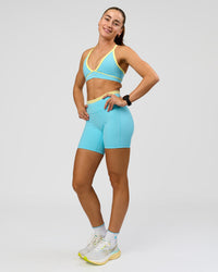 Woman wearing Lume Fusion Mid-Rise V Contour 6" Short Pockets - Baltic Sea-Lemon | Model:Grace | Size:XS