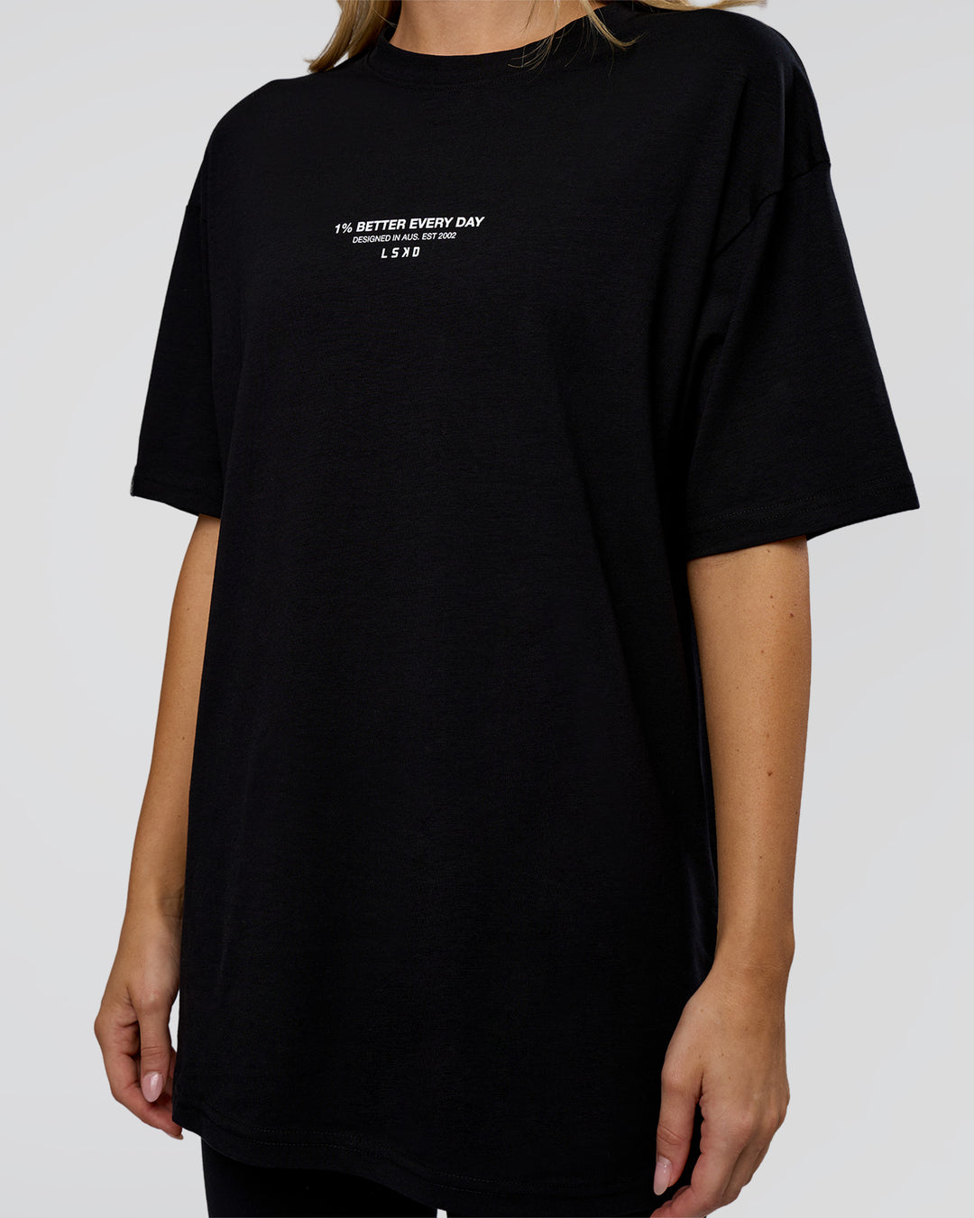 Woman wearing 1% Better Every Day EST FLXCotton Oversized Tee - Black | Model:Leilani | Size:XS
