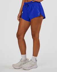 Woman wearing Accelerate 3" Mid-Rise Running Short - Electric Indigo | Set:true | Angle:side | Model:Brylee | Size:XS