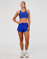 Woman wearing Accelerate Split Strap Sports Bra - Electric Indigo | Model:Emelia | Size:XS