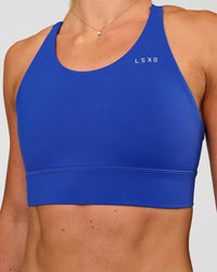 Woman wearing Accelerate Split Strap Sports Bra - Electric Indigo | Model:Emelia | Size:XS