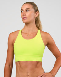 Woman wearing Accelerate Split Strap Sports Bra - Hyper Green | Model:Emelia | Size:XS