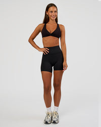 Woman wearing Aspire Twist Sports Bra - Black | Model:Brylee | Size:XS