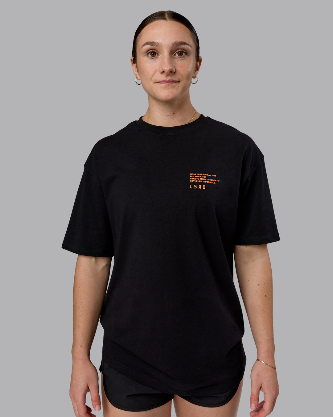 Woman wearing Coffee Run FLXCotton Oversized Tee - Black-Ultra Orange | Model:Sav | Size:XS