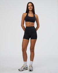 Woman wearing Elite High-Rise 4" Short Pockets - Black | Model:Eliza | Size:XS