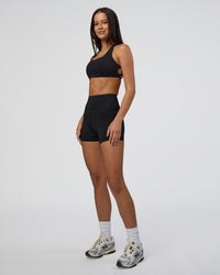 Woman wearing Elite High-Rise 4" Short Pockets - Black | Model:Eliza | Size:XS