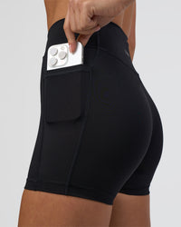 Woman wearing Elite High-Rise 4" Short Pockets - Black | Model:Eliza | Size:XS