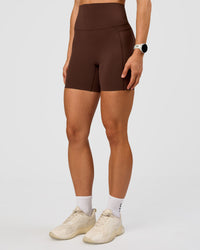 Woman wearing Elixir Ultra High-Rise 6” Short Pockets - Hot Chocolate | Model:Maja | Size:XS