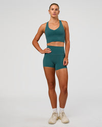 Woman wearing Evoke Longline Sports Bra - Transformative Teal | Model:Emelia | Size:XS