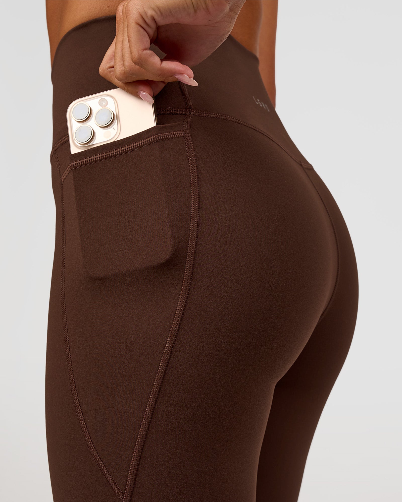Woman wearing Fusion Ultra High-Rise 9" Short Pockets - Hot Chocolate | Model:Charli | Size:XS