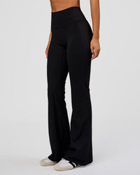 Woman wearing Fusion V-Contour High-Rise Flared Legging Pockets - Black | Model:Charli | Size:XS