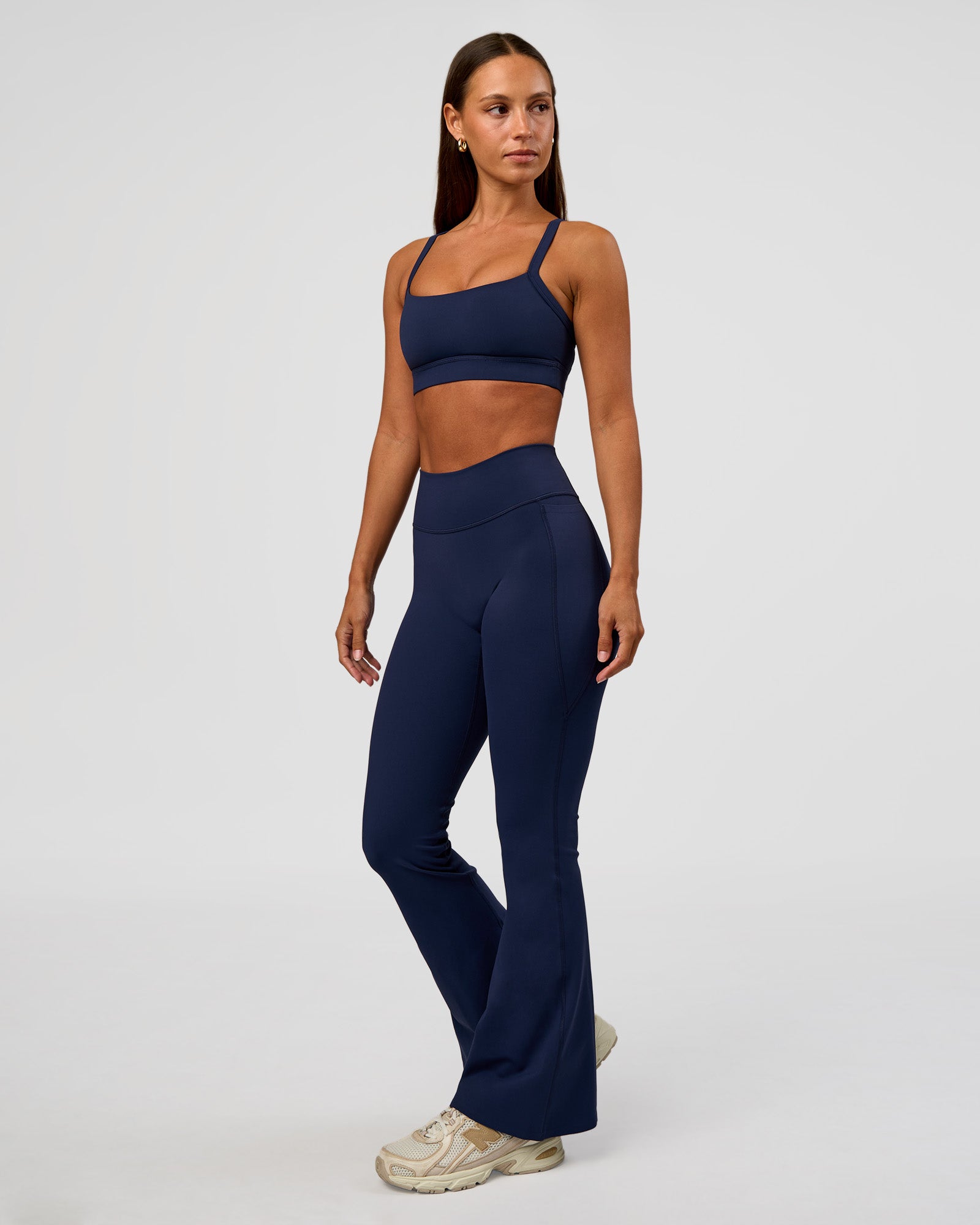 Woman wearing Fusion V-Contour High-Rise Flared Petite Legging Pockets - Future Navy | Model:Brylee | Size:XS