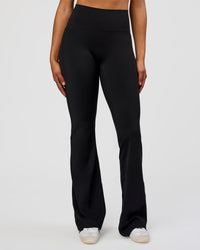 Woman wearing Fusion V-Contour High-Rise Flared Tall Legging Pockets - Black | Model:Rosie | Size:S